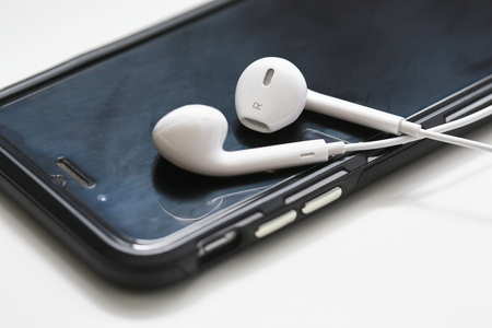 NAKHONRATCHASIMA, THAILAND - JUL 2, 2018 : Smartphone and earphone on white table with in the background.のeditorial素材