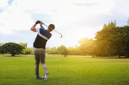 Man hitting golf shot with club on course while summer in the sun.の写真素材