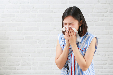 Young woman having sneeze on  background.の写真素材