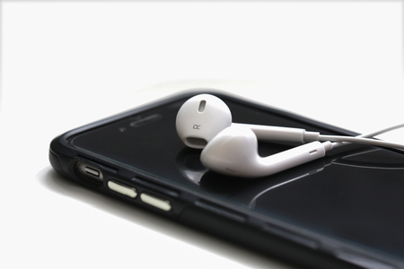 Smartphone and earphone on white table with in the background.の写真素材