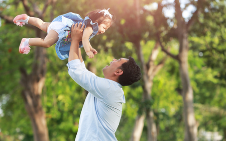 Father throw up daughter in the air  on the park.の写真素材