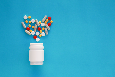 Pills heart out of pill bottle on blue background, top viewの写真素材