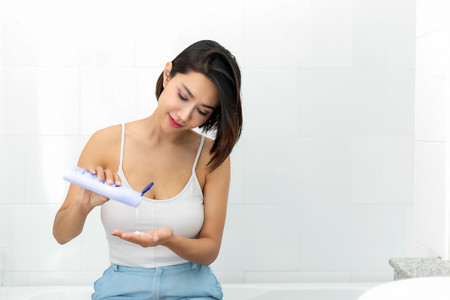 Beautiful young woman in underwear applying body lotion.の写真素材