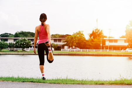 Sporty woman doing morning stretching and warming before city workout sessionの写真素材