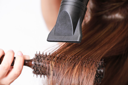 Beautiful young woman is using a hair dryer.の写真素材