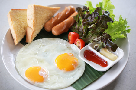 Plate of breakfast with fried eggs, sausage and vegetables.の写真素材