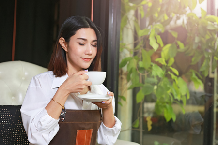 Closeup of a asian woman holding and drinking hot coffee with feeling good.の写真素材