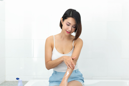 Young woman applying body lotion cream after bath.の写真素材