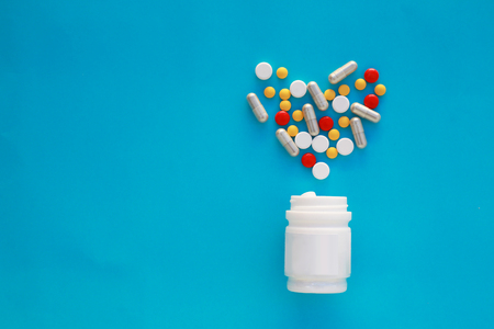 Pills heart out of pill bottle on blue background, top viewの写真素材