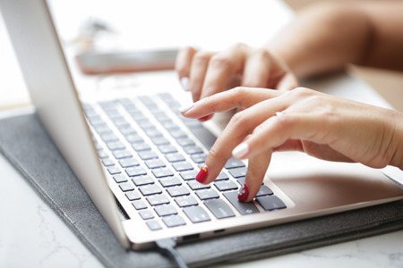 Woman sitting at desk and working at computer close up in hands.の写真素材