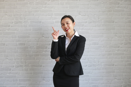 Young beautiful businesswoman smiling looking at camera pointing finger in side over white background.の写真素材