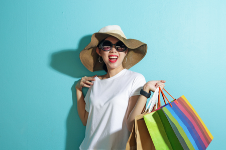 Portrait of beautiful girl holding shopping bags isolated over blue background.の写真素材