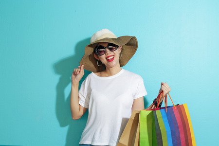 Portrait of beautiful girl holding shopping bags isolated over blue background.の写真素材
