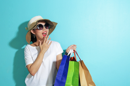 Portrait of beautiful girl holding shopping bags isolated over blue background.の写真素材
