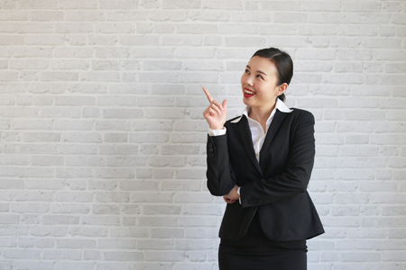 Young beautiful businesswoman smiling looking at camera pointing finger in side over white background.の写真素材