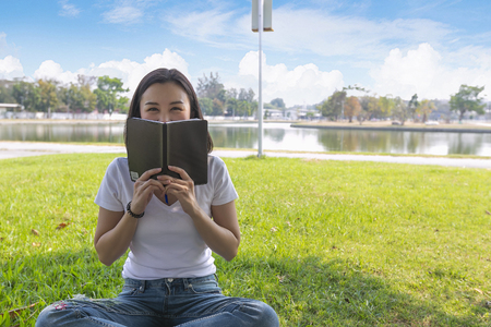 Woman reading book at park in the evening light.の写真素材