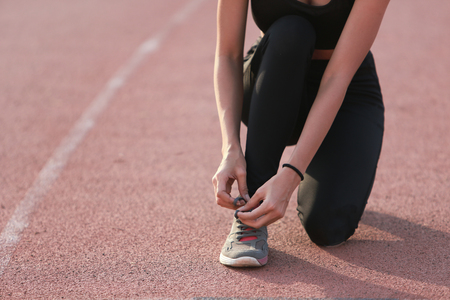 Asia woman runner tying her shoes preparing for a run on lane.の写真素材