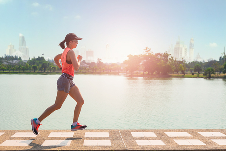 Beautiful woman running over bridge during sunset in the park.の写真素材