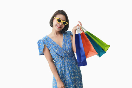 Portrait of beautiful girl wearing dress and sunglasses holding shopping bags.の写真素材