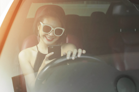 Young woman driving the car and talking phone on the road.の写真素材