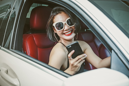 Young woman driving the car and talking phone on the road.の写真素材