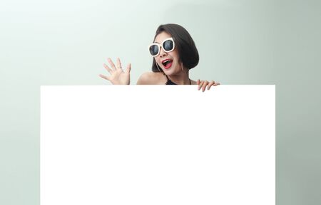 Young beautiful girl smiling and holding a blank sheet of paper.の写真素材
