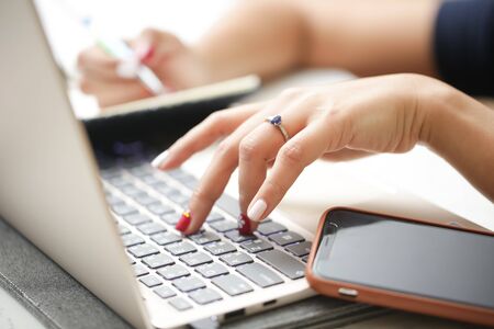Woman sitting at desk and working at computer close up in hands.の写真素材