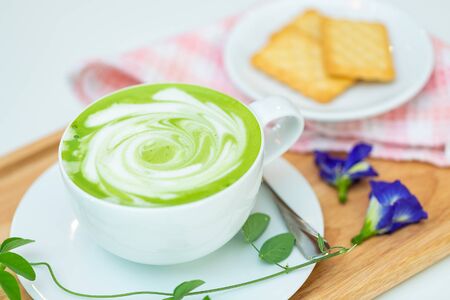 Hot green tea milk with cracker and spoon.の写真素材