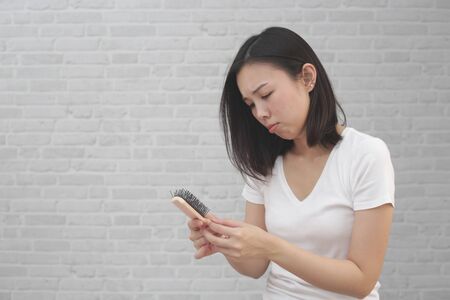 Girl with a comb and problem hair loss on background.の写真素材