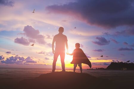 Super Son holding hand of fatheroutdoors on background sunset. Father holidayの写真素材