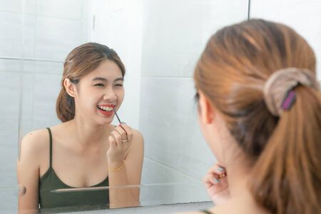 Asian women happiness makeup by red lipstick with mirror in bathroom.の写真素材