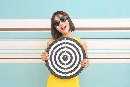 Goals concept with young woman holding target on blue background.の写真素材