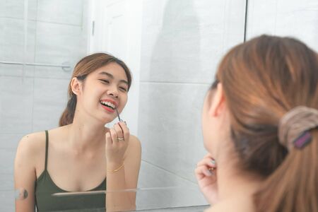 Asian women happiness makeup by red lipstick with mirror in bathroom.の写真素材