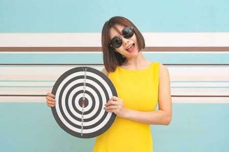 Goals concept with young woman holding target on blue background.の写真素材