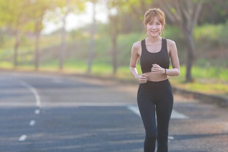 Young asian woman in sport wear running in the park.の写真素材