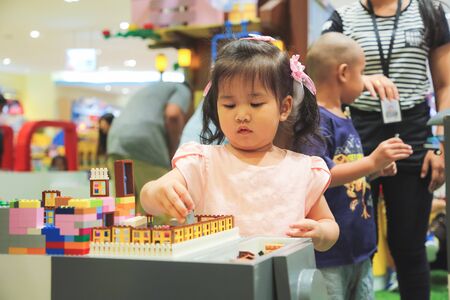 Little girl build a tower and funny with educational toy blocks.の写真素材