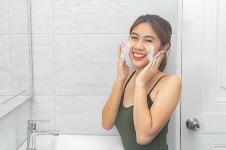 Beautiful young woman washing her face foam in a bathroom.の写真素材