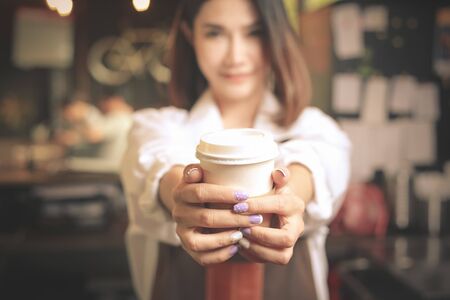 Young asian women barista hold coffee cup serving at the coffee shop.の写真素材