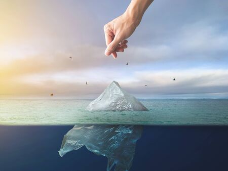 Hand throwing plastic bag floating in ocean, environment pollutionの写真素材