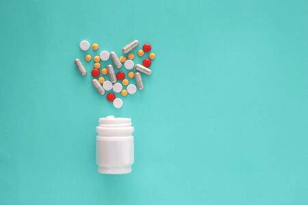 Pills spilling out of pill bottle and isolated on green background.の写真素材