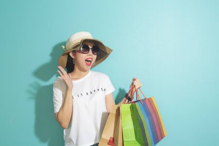 Portrait of beautiful girl holding shopping bags isolated over blue background.の写真素材