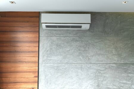 Living room with gray wall and wooden air conditioner on wall.の写真素材