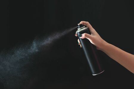 Hand using a spray, isolated on black background.の写真素材