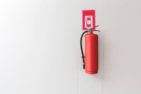 Red Fire extinguisher on the white wall background.の写真素材