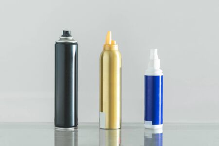 Three multicolored bottles of professional hair spray on white background.の写真素材