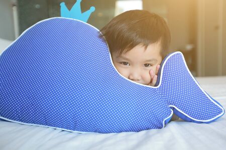 Cute asian boy children lying on with pillow on bed.の写真素材