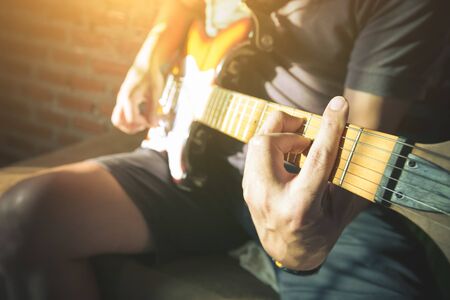 Close-up Man hands playing acoustic guitar with light flare.