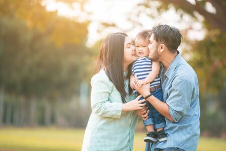 Family of happy couple with baby in park outdoors.の写真素材