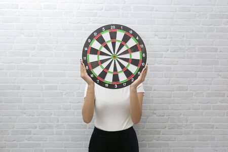 Goals concept with young woman holding target on blue background.