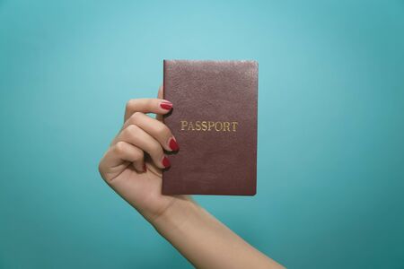 Image of a persons hand holding a passport on blue background.の写真素材